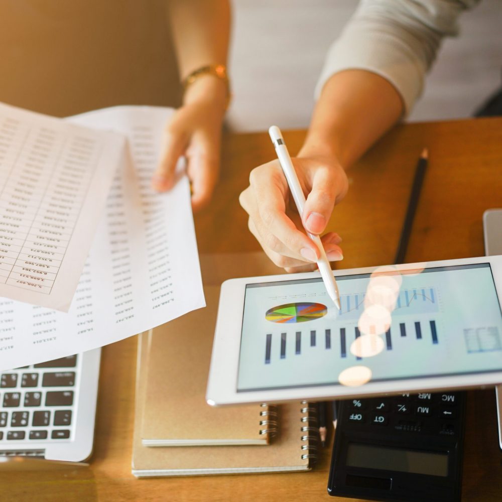 close up group of businessman use stylus pen for explaining dashboard about company's profit monthly on tablet and businesswoman holding report paper for collaborate  work at meeting event , business finance concept